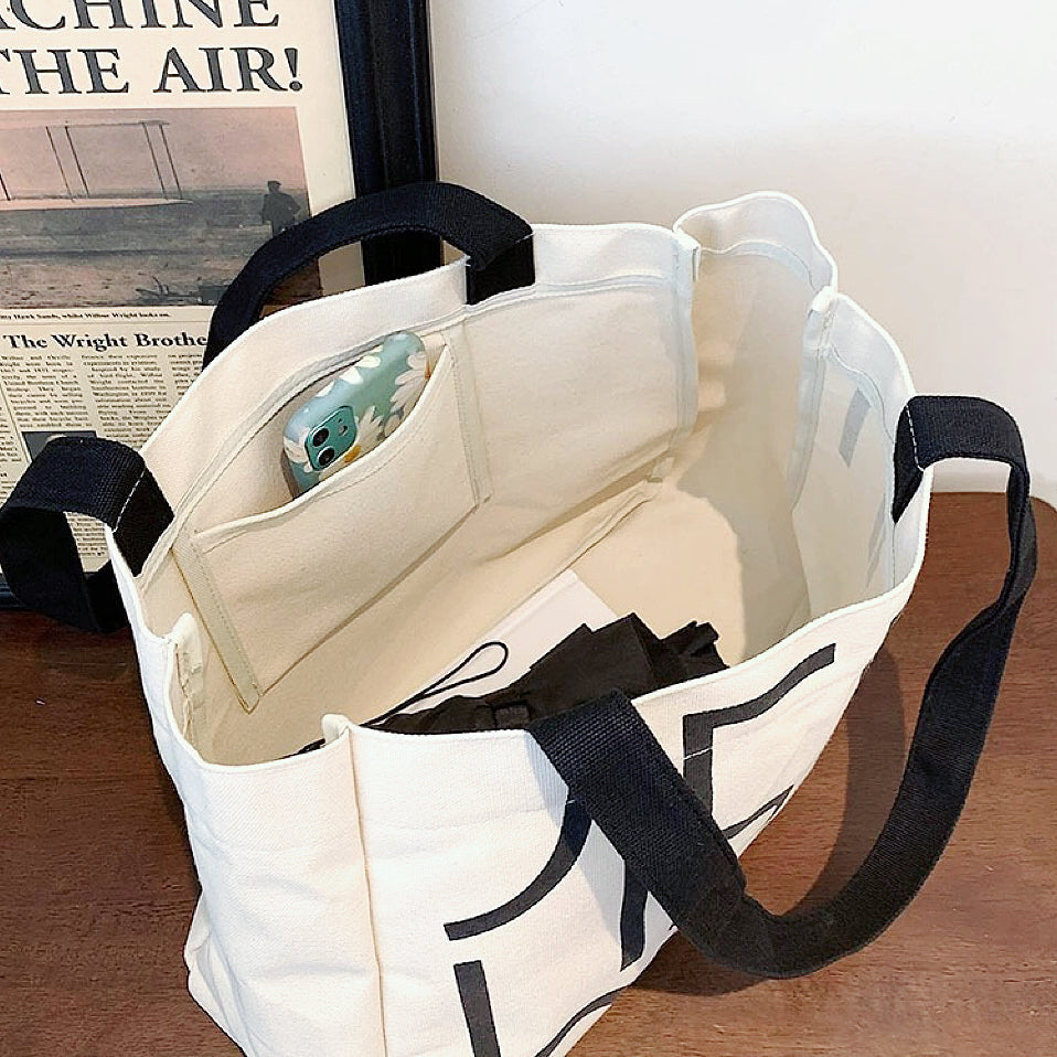 Interior view of the white canvas tote showing the inner pocket for organization and high-density material.