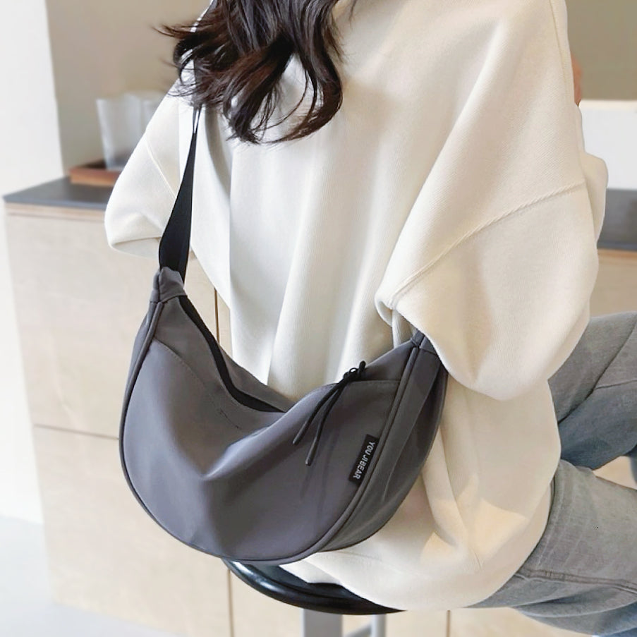 Close-up of model wearing the grey crescent bag; highlight of the high-density nylon texture and adjustable strap length.