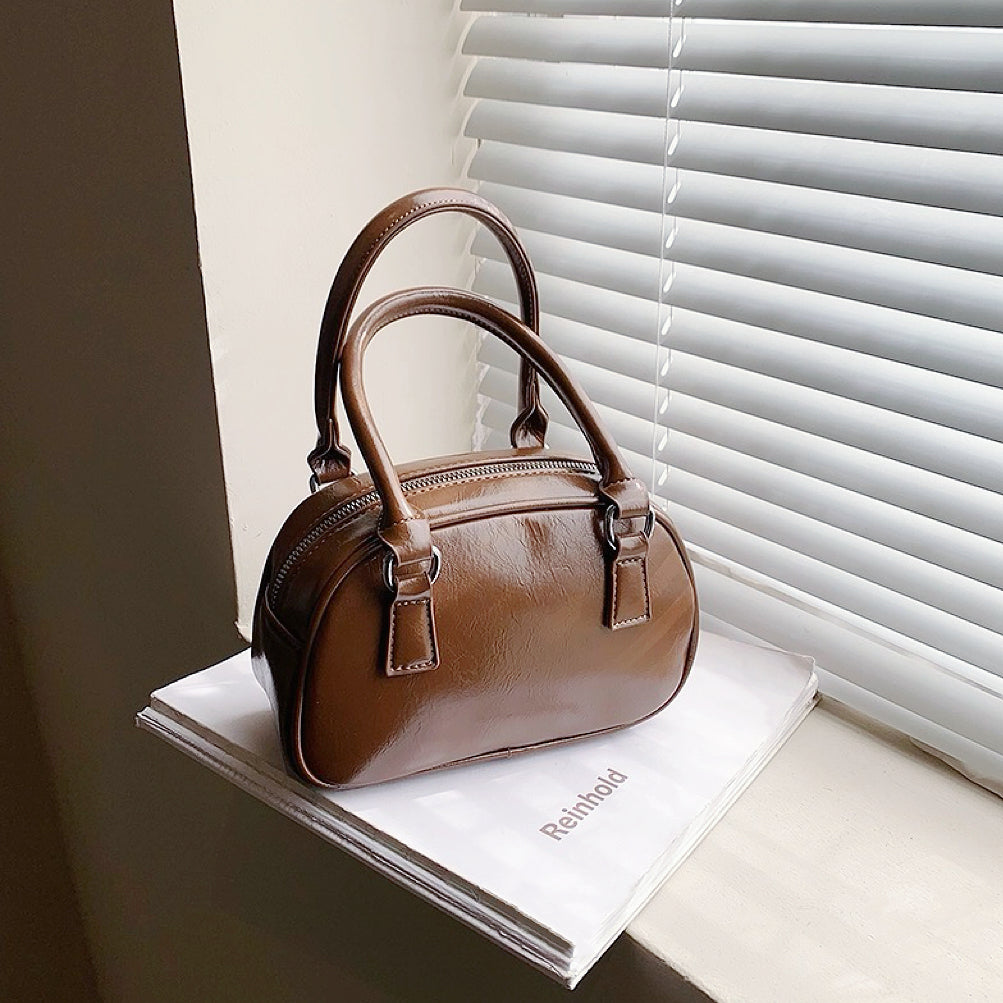 Angled view of Mini Leather Bowling Bag in brown, great for everyday carry and travel.