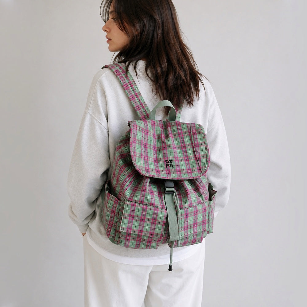 Back view of a model wearing the pink and green plaid laptop backpack flat against the lower back.