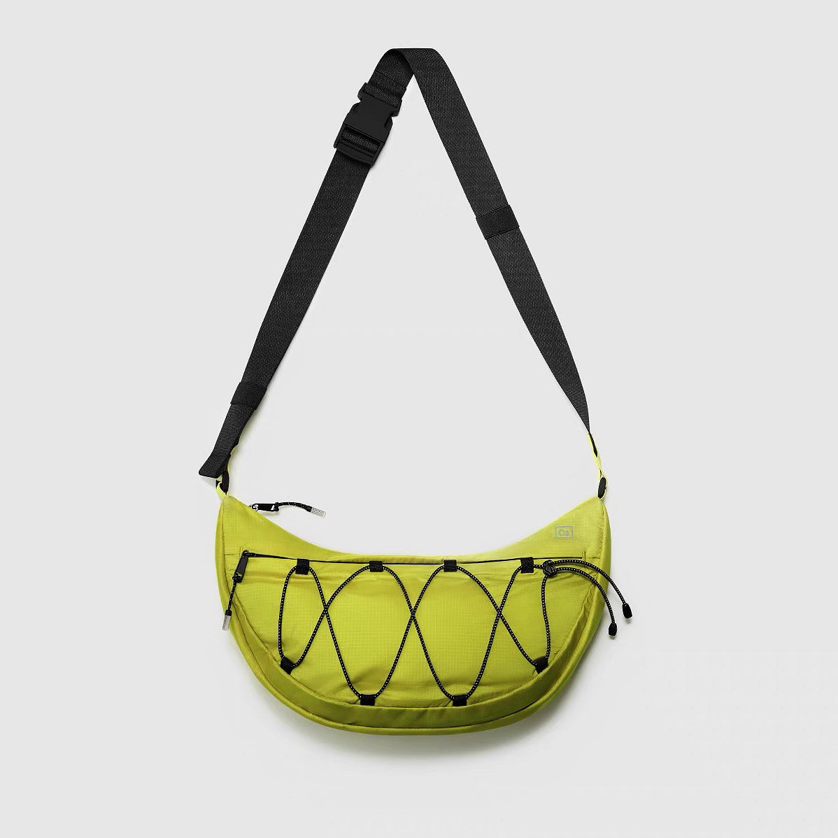 Close-up of the mustard nylon crossbody bag with a minimalist silhouette and bungee detail.