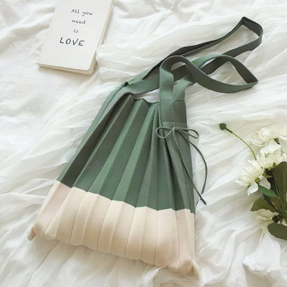 Folded view of Green and cream accordion foldable knitted  bag with shoulder straps.