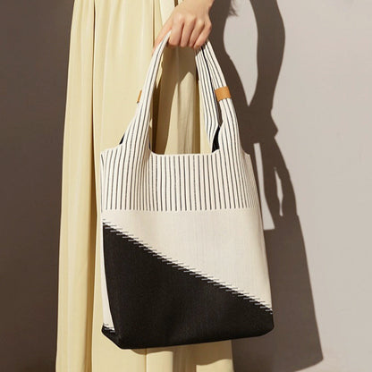 Model carrying white and black knitted artistic tote bag showcasing artisanal style for creative professional commutes.
