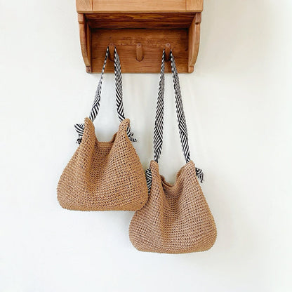 Two straw bags with different straps lengths hang on the wall: one features shoulder strap, the other has crossbody strap.