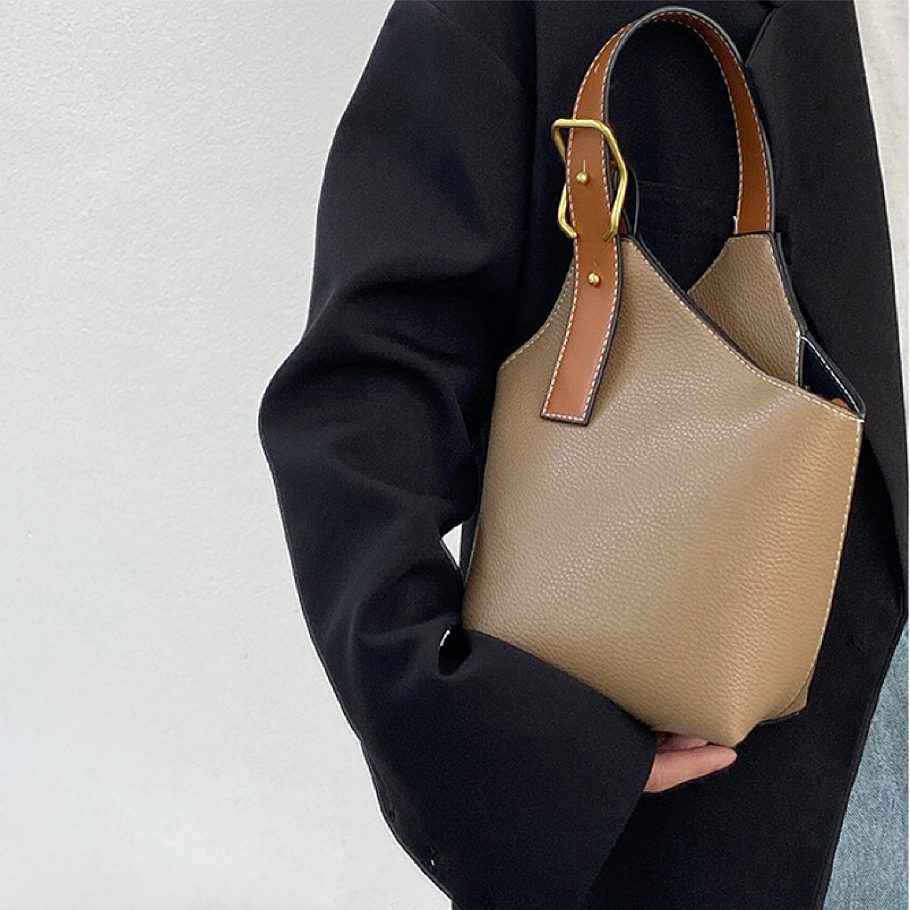 Model carrying a khaki balloon bucket bag handheld, easy for commuting and weekends.