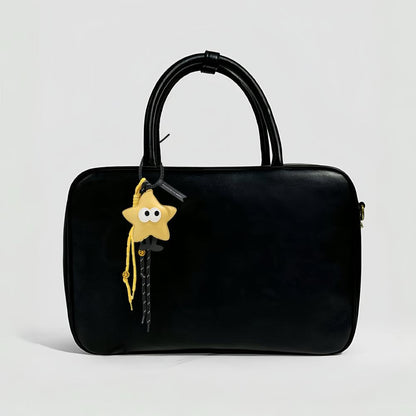 Yellow Big Eyed Stars bag charm hanging on a black bag, great for winter looks and travel days.