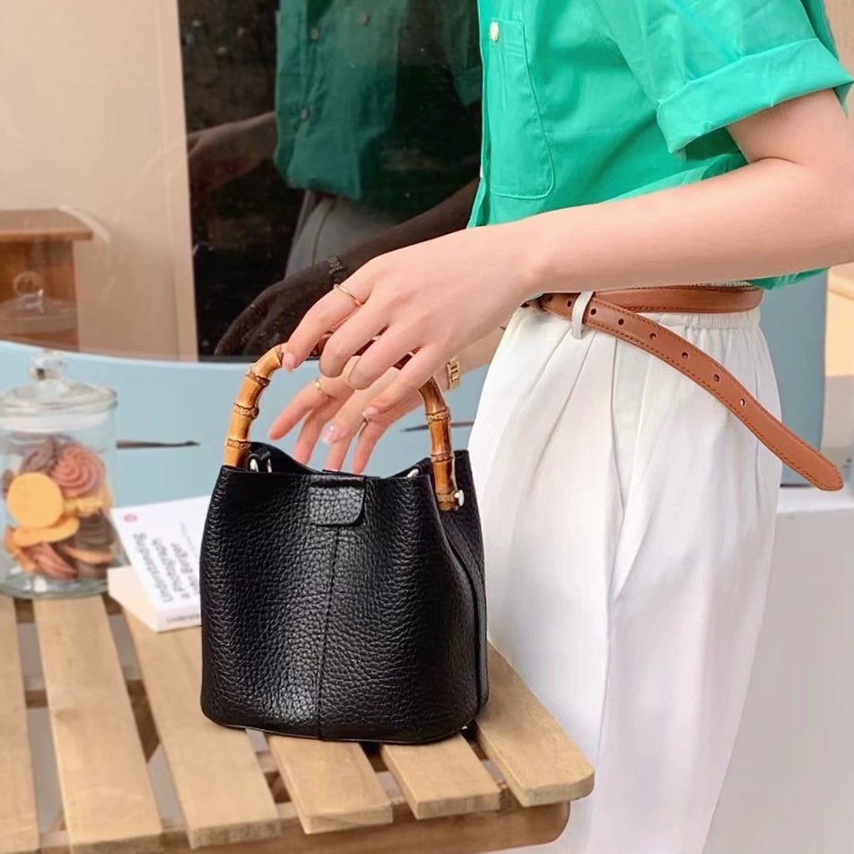 A model carrying the bamboo handle bucket bag in black, showcasing its elegant vintage aesthetic for daily wear.