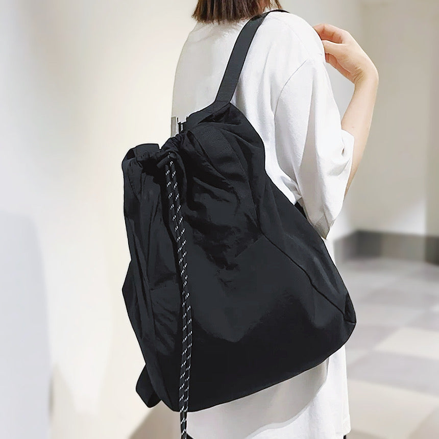 Rear view of the black 2-way bag used as a backpack, demonstrating the comfortable shoulder straps and drawstring detail.