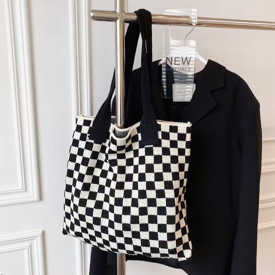 Black and white checkered knit tote hanging on a rack, perfect for a minimalist wardrobe.