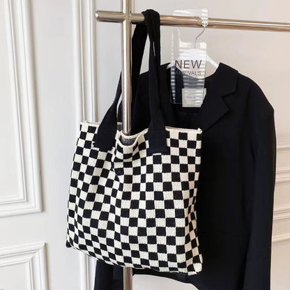 Black and white checkered knit tote hanging on a rack, perfect for a minimalist wardrobe.