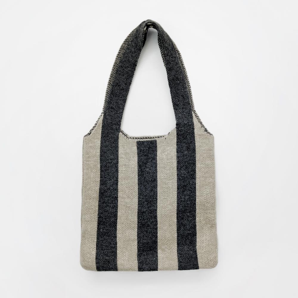Close-up of Wool blend knit bag with bold black and beige vertical stripes and a shoulder strap wool shoulder bag.