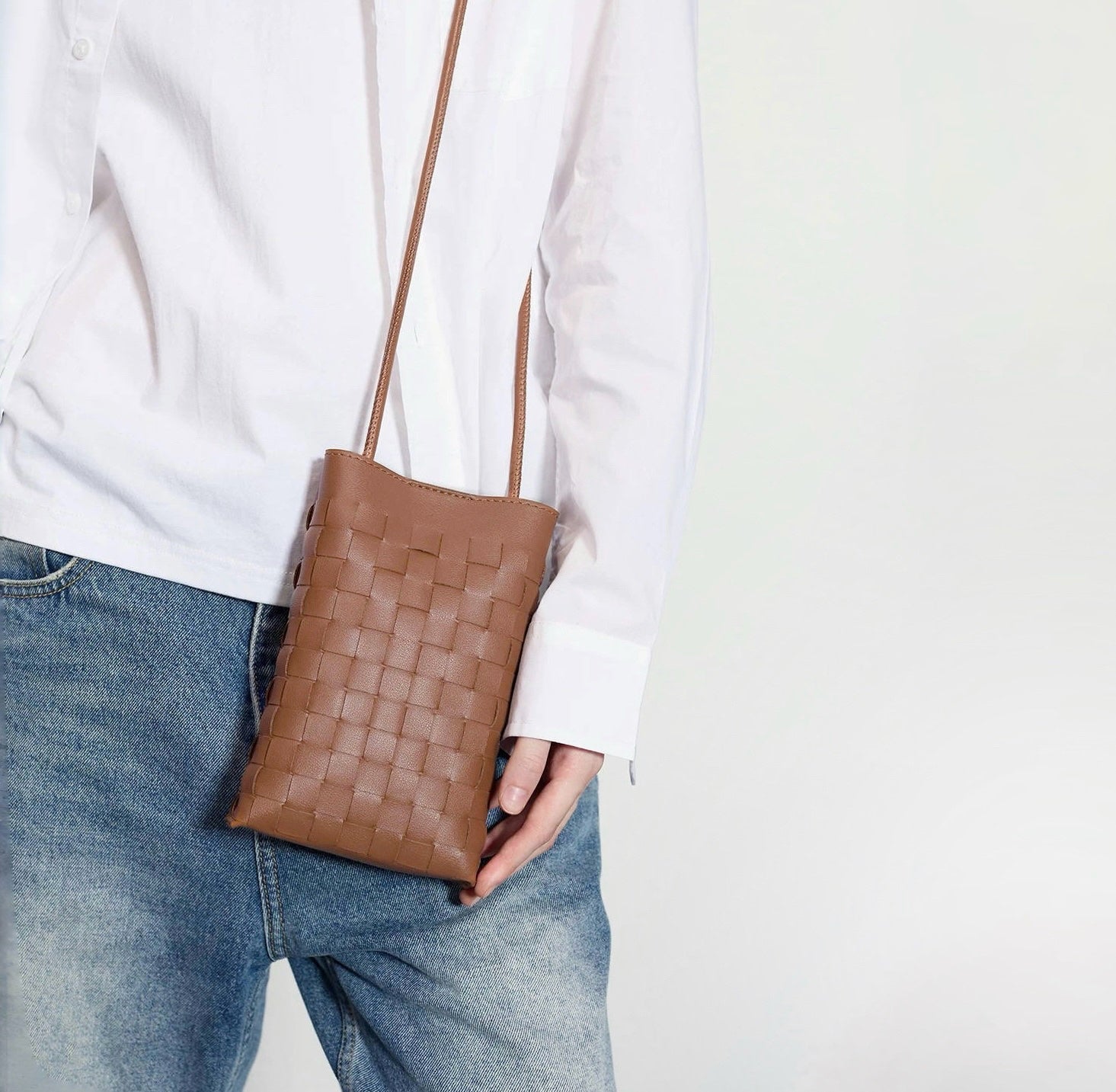 Model carrying a brown Braid Elegance Crossbody Bag handheld , great for daily carry and travel.