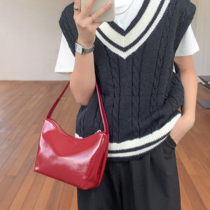 Model wearing the red patent leather shoulder bag as an underarm bag; perfect for retro-chic fashion.