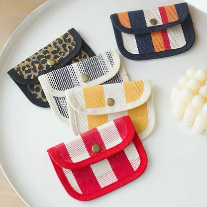 Assorted canvas coin purses with snap flap: red stripe, yellow gingham, leopard, and plaid patterns for small cash.
