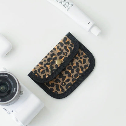 Leopard print canvas coin purse with black trim; snap-flap pouch for coins, lip balm, and small items.