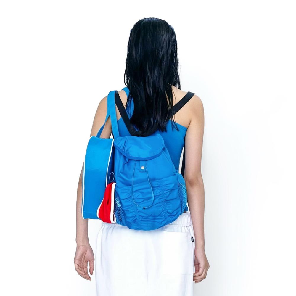 Model wearing the blue pleated backpack; vibrant aesthetic perfect for active urban lifestyle and street styling.