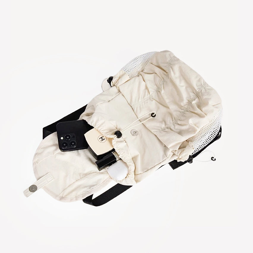 Close-up of cream pleated backpack lying flat; showcases high-quality nylon texture and reinforced drawstring details.