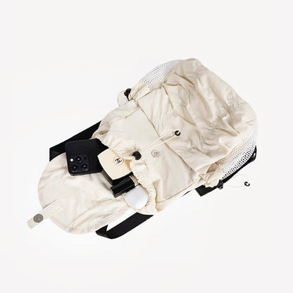 Close-up of cream pleated backpack lying flat; showcases high-quality nylon texture and reinforced drawstring details.