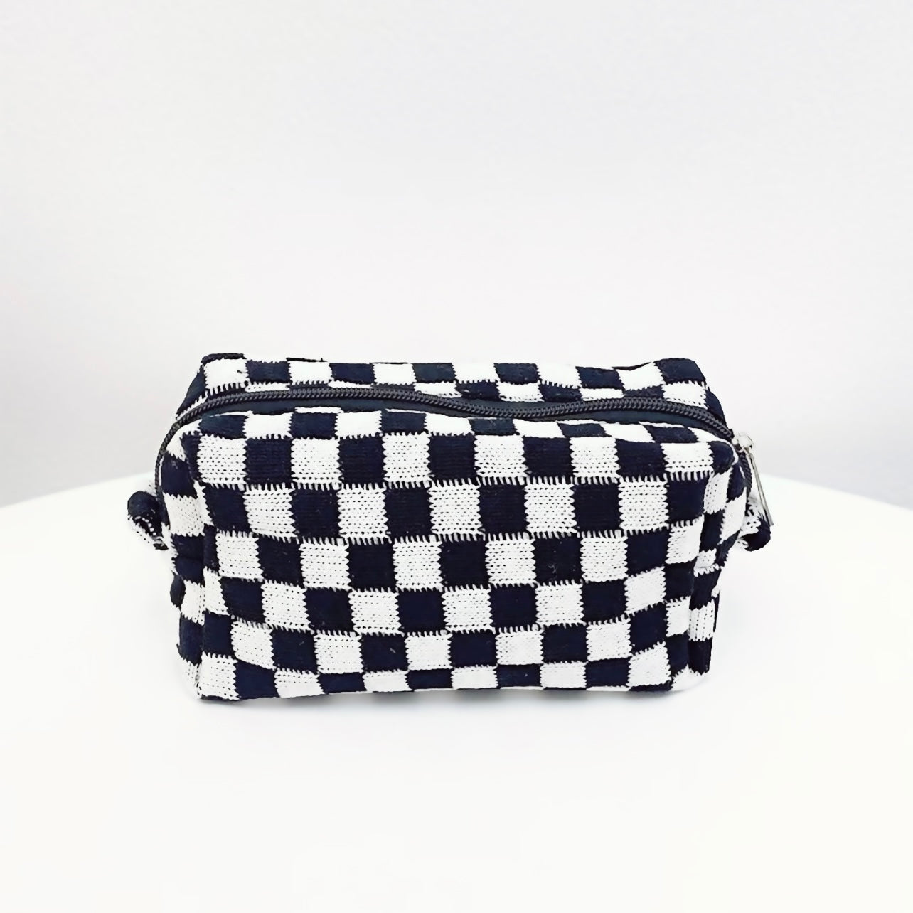 Classic black and white checkerboard knit bag; durable woven cosmetic pouch for timeless aesthetic fashion.
