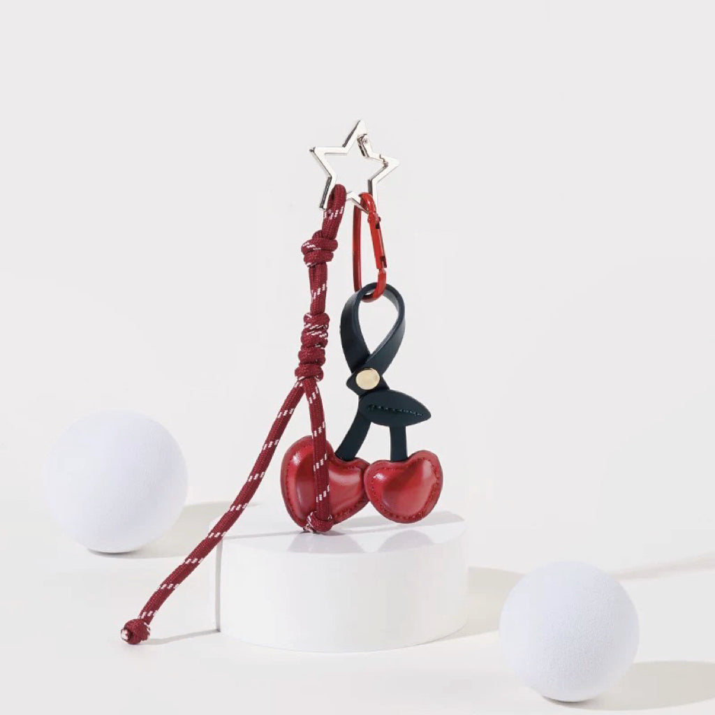 Angled view of Cherry Bag Charm with cherry and rope, easy to attach to bags and phones.