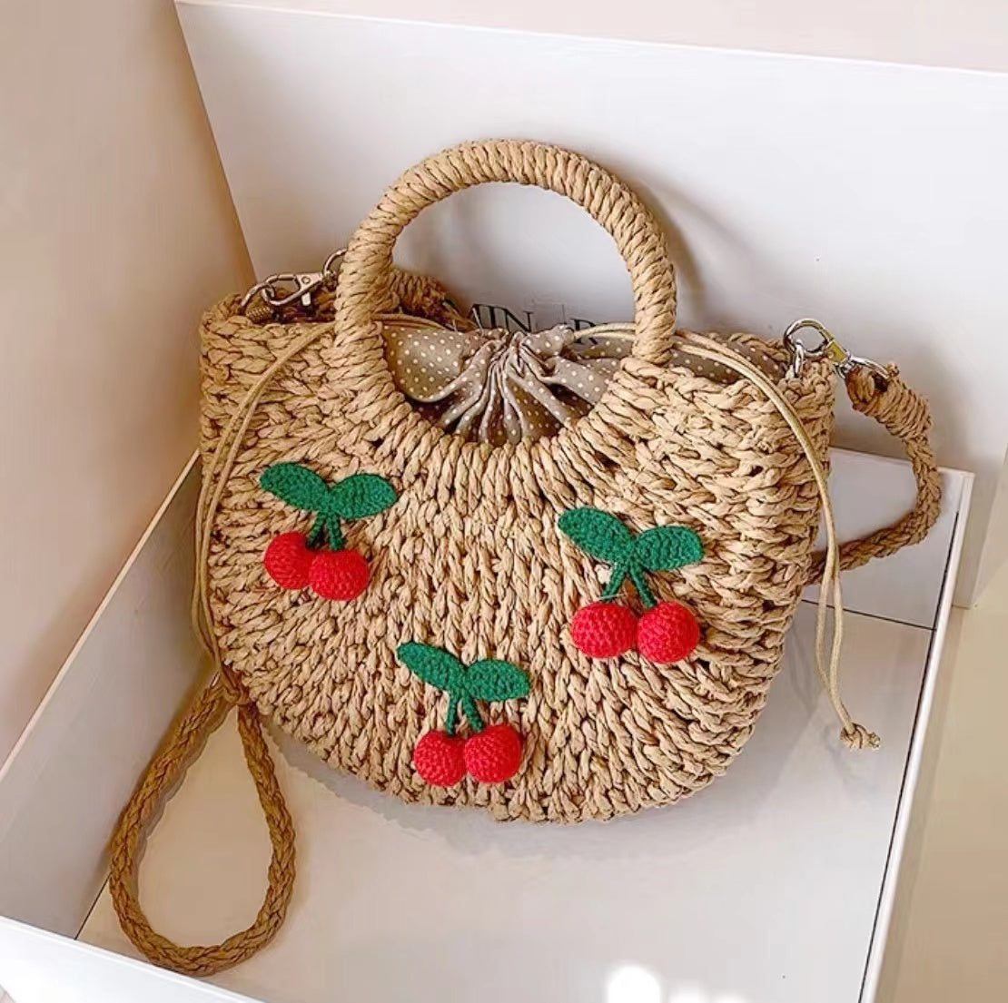 Front view of rattan straw bag with  red cherry appliques and polka dot lining, great for everyday.