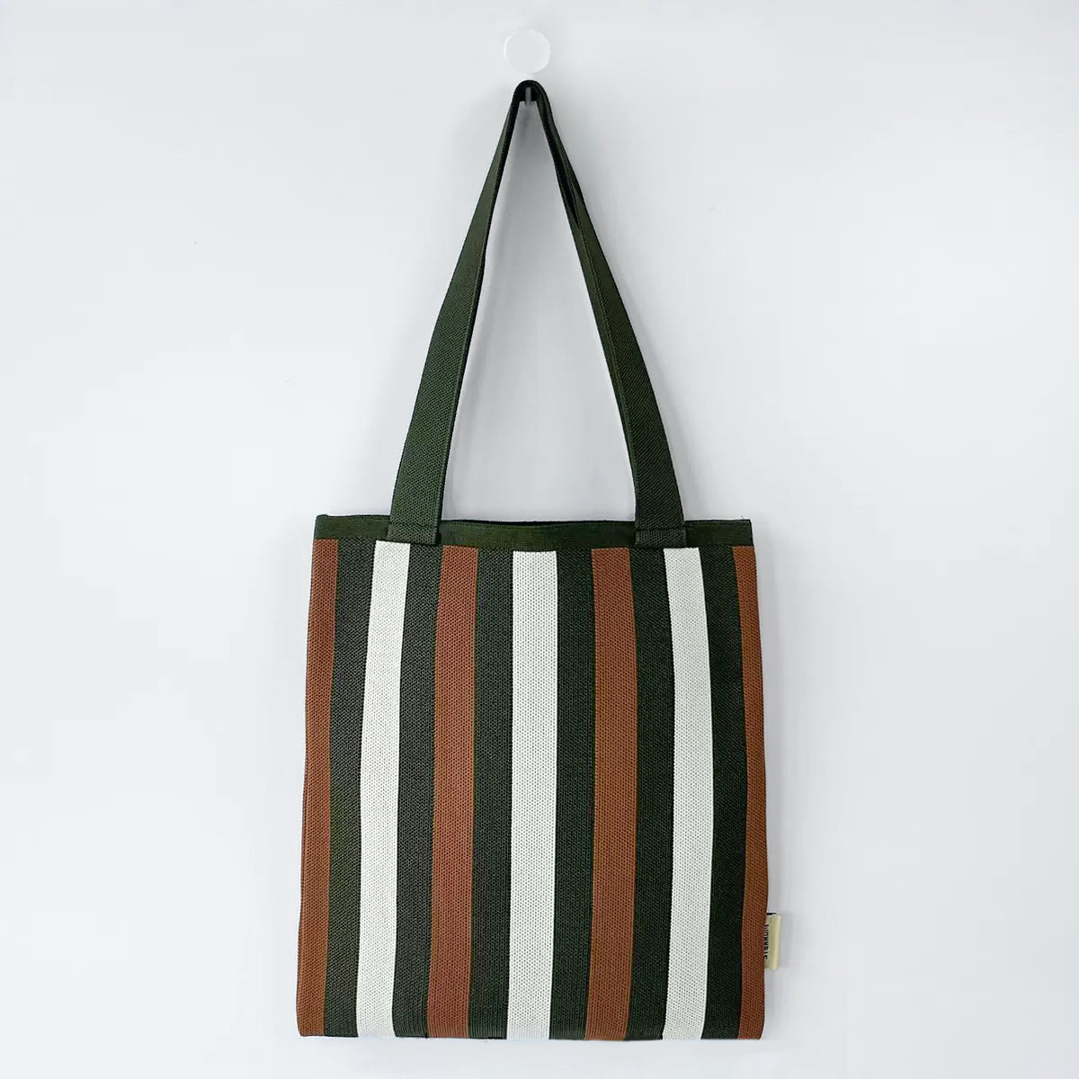 Close-up of Polyester knitted tote bag with vertical stripes in dark green, brown, and white.