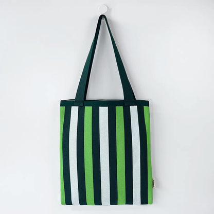 Flat lay of Chromatic Stripe Knitted Bag in white and green, great for everyday carry and travel.