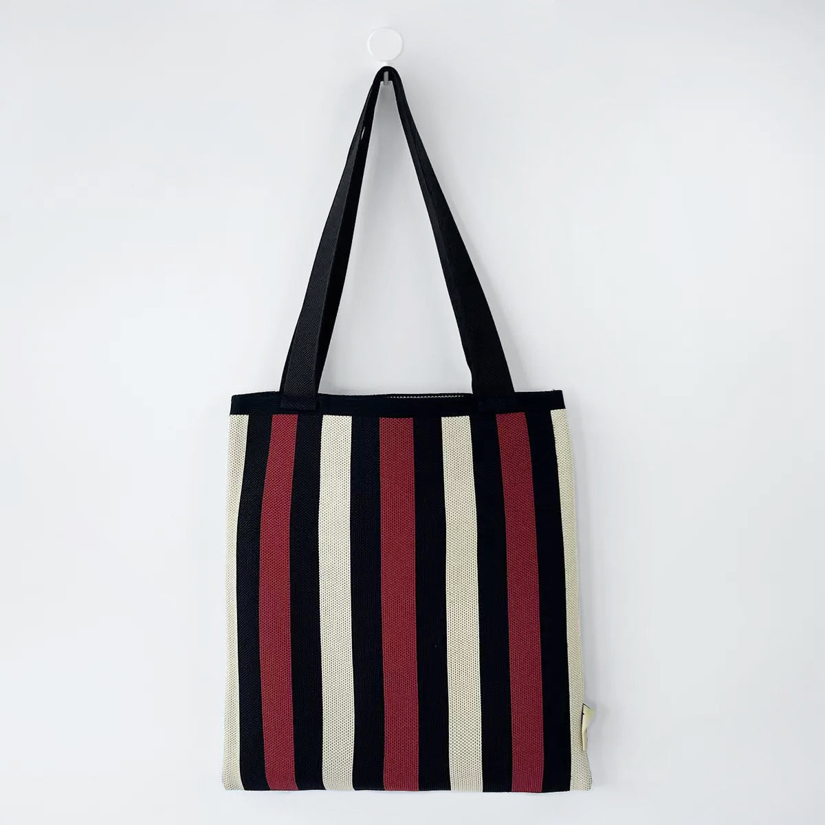 Folded view of Chromatic Stripe Knitted Bag in black and red, easy for commuting and weekends.
