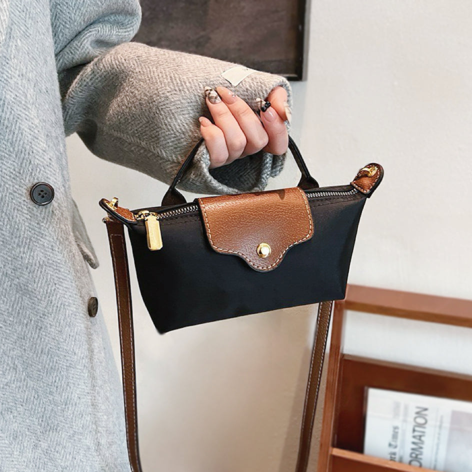 Detailed shot of a model holding the classic black mini nylon bag by its top handle.
