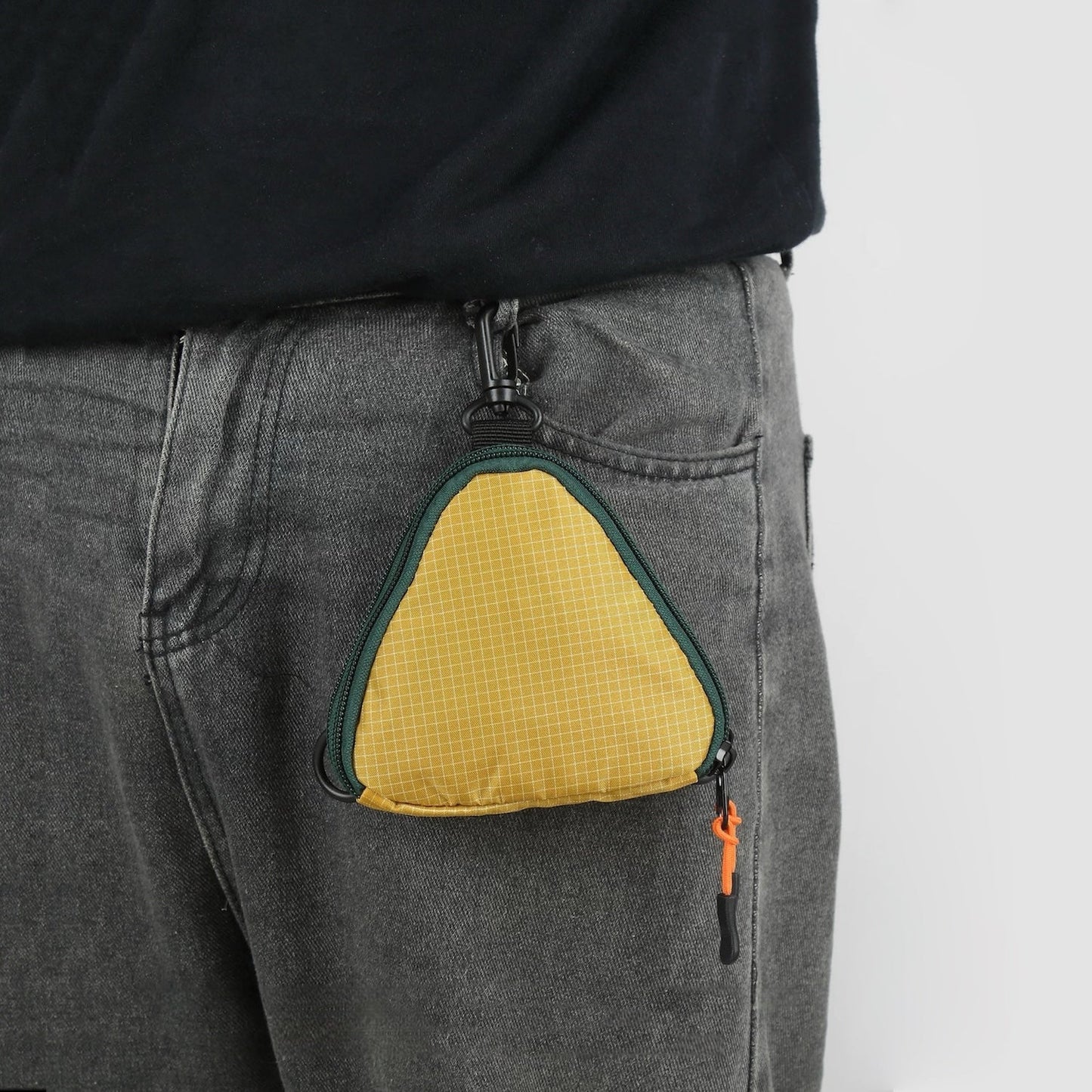 Close-up of a triangle multi-use bag clipped to a belt loop, showing hands-free storage for keys and cards.