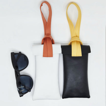 White and black glasses cases with sunglasses, portable wristlet design perfect for hands-free beach trips.