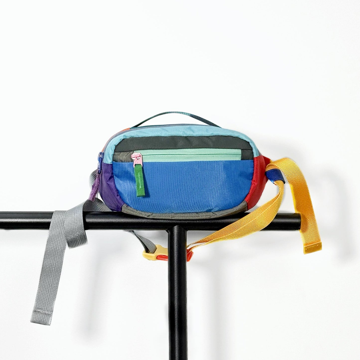 Blue nylon belt bag displayed on a black metal stand and clean background.
