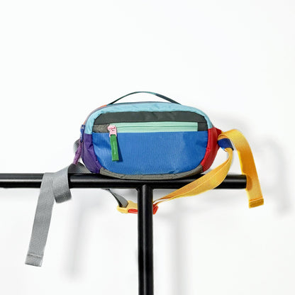 Blue nylon belt bag displayed on a black metal stand and clean background.