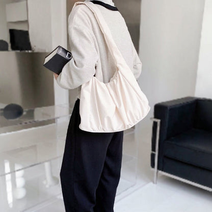 Side view of model styling the cream white pleated bag; versatile neutral accessory for summer outings and minimalist fashion.