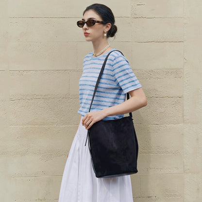 Model wearing the black suede bag, showing the long shoulder carry.