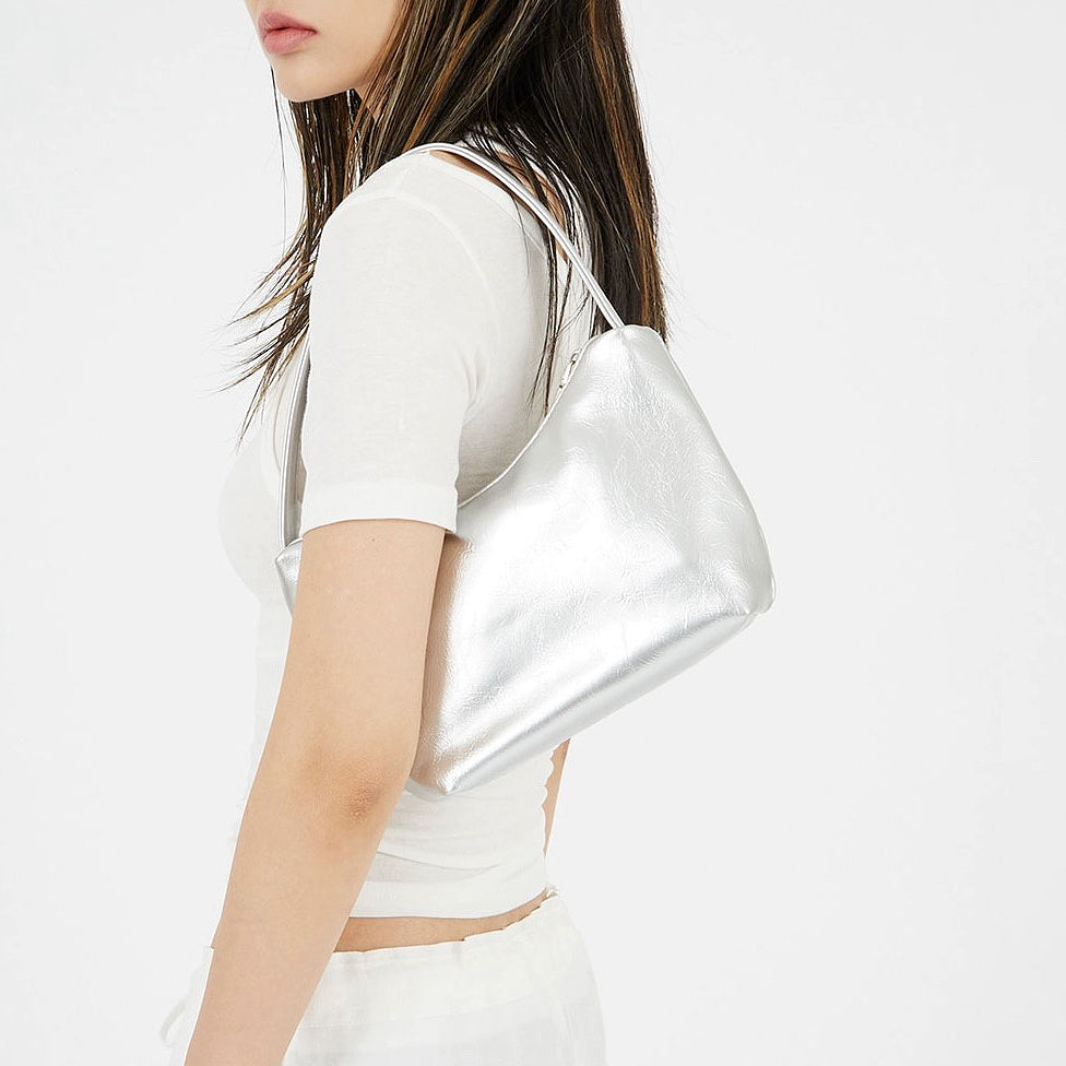 Model carrying a silver  patent leather bag on the shoulder, ideal for city walks and gifting.