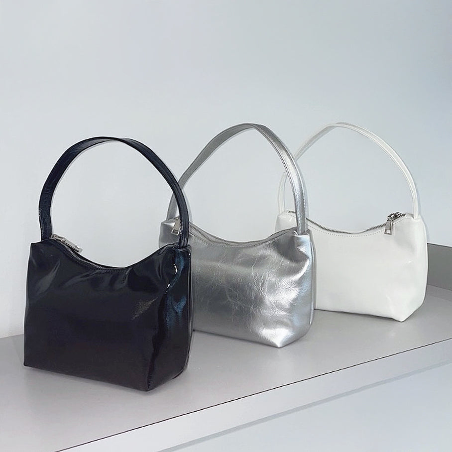Front view of Three cool patent leather shoulder bags in black, silver, and white, featuring a sleek, compact design.
