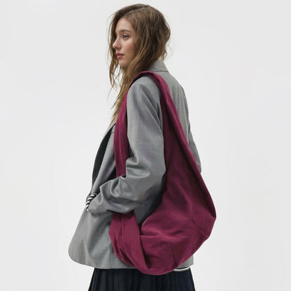 Model styling the rich burgundy corduroy crescent bag with a grey blazer.