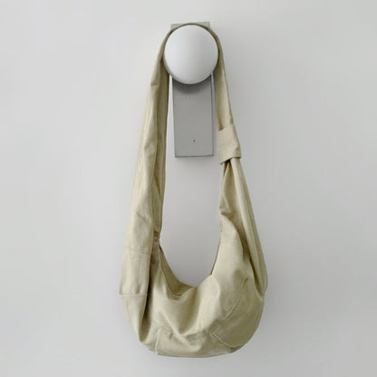Khaki corduroy crescent bag hanging on a minimalist wall hook.