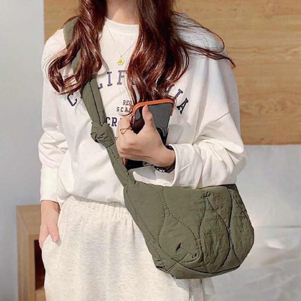 Model wearing the olive green quilted crescent crossbody bag, showing its lightweight and puffy design.