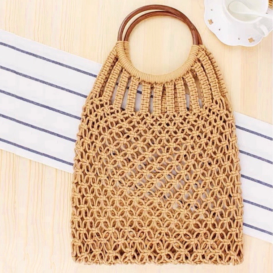 Angled view of camel cotton crochet handbag with round wooden ring handles, featuring an open-weave macrame design.