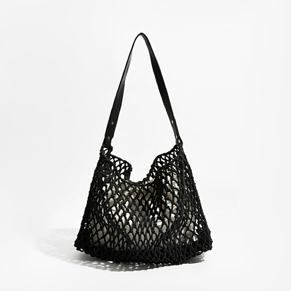 Angled view of Black crochet shoulder bag with a long leather strap and cotton rope net design, easy for commuting.