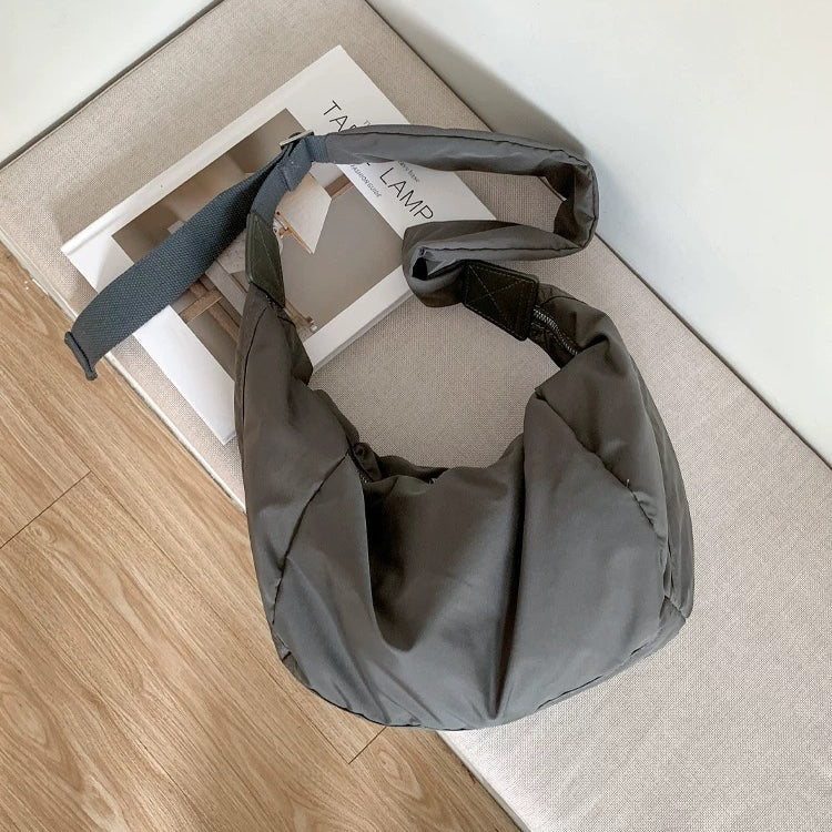 Dark grey crescent bag with a soft, padded silhouette and durable nylon texture.