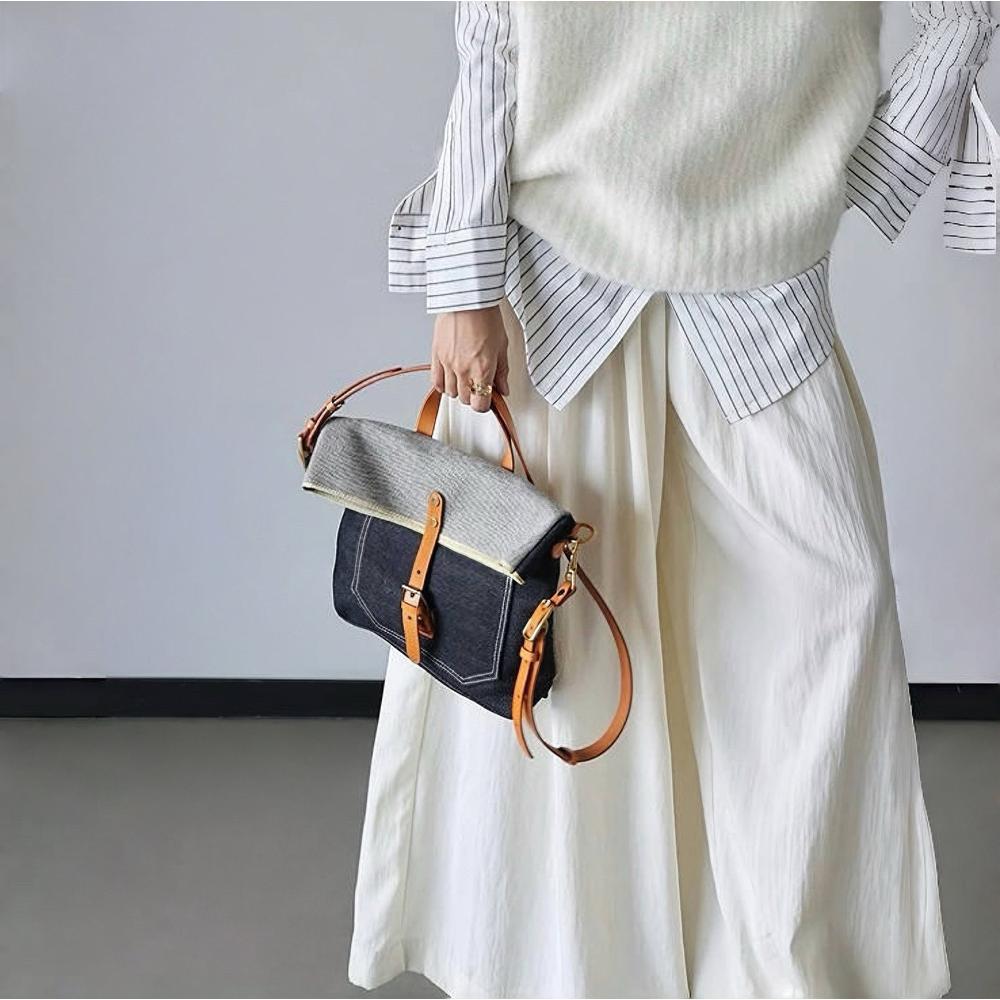 Model carrying a  Denim Trimmed Messenger Bag handheld, great for daily carry and travel.