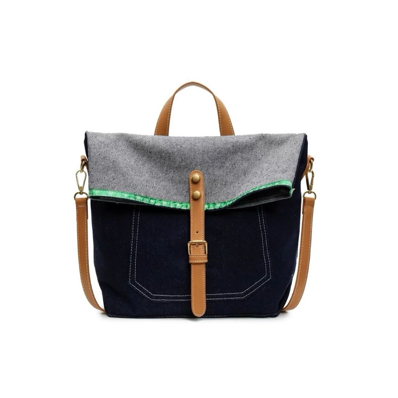 Front view of Denim trimmed messenger bag with gray flap, brown straps, magnetic closure, and green accent.