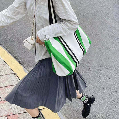 Model carrying the green and white striped canvas tote bag on the street.