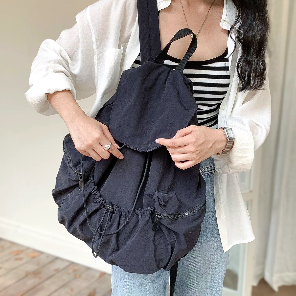 Model styling a black nylon backpack; ultralight material ideal for  city commuting.