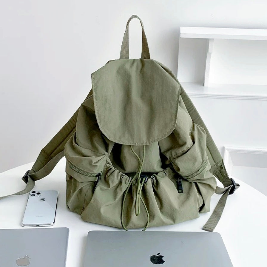 Front view of Olive green ultralight backpack with side zip pockets; durable nylon suited for outdoor-inspired street style.