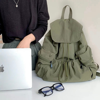 Olive ultralight backpack shown with a laptop and glasses; perfect setup for digital nomads and remote work.