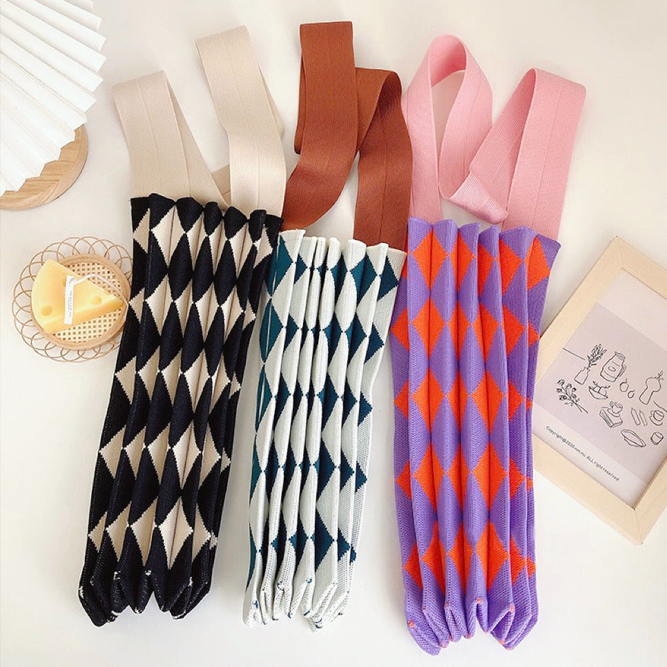 Three argyle knitted bags rolled up to show compact storage and stretchable material.